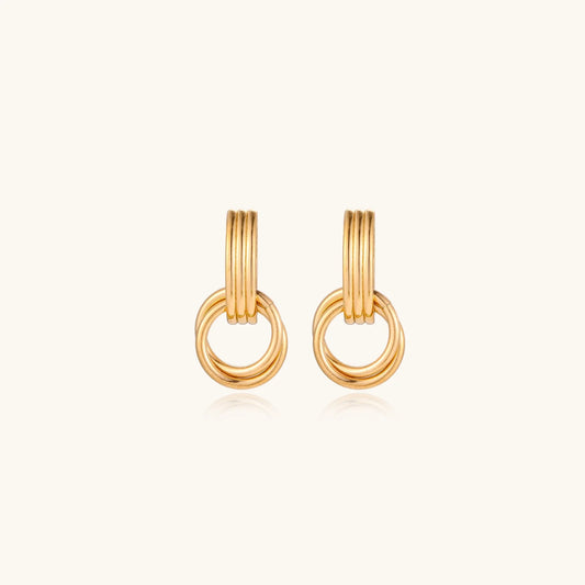 Gold stud earrings with vertical ridged bar connecting to triple interlocking circular rings on white background